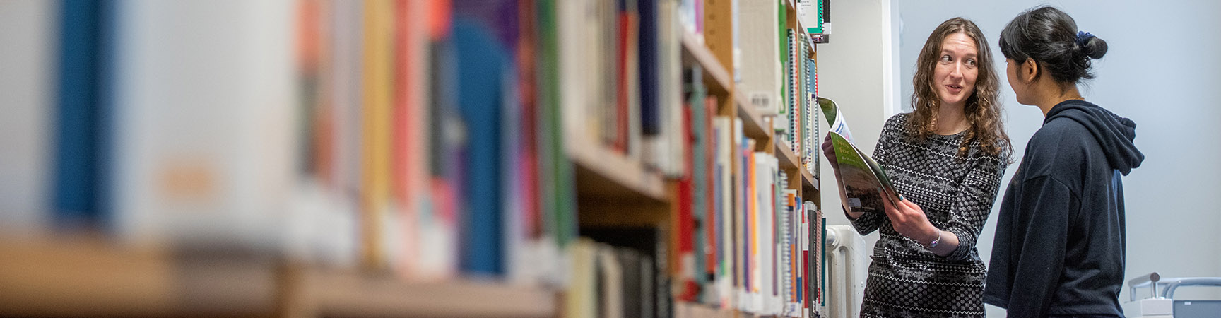 A librarian shows a student a book