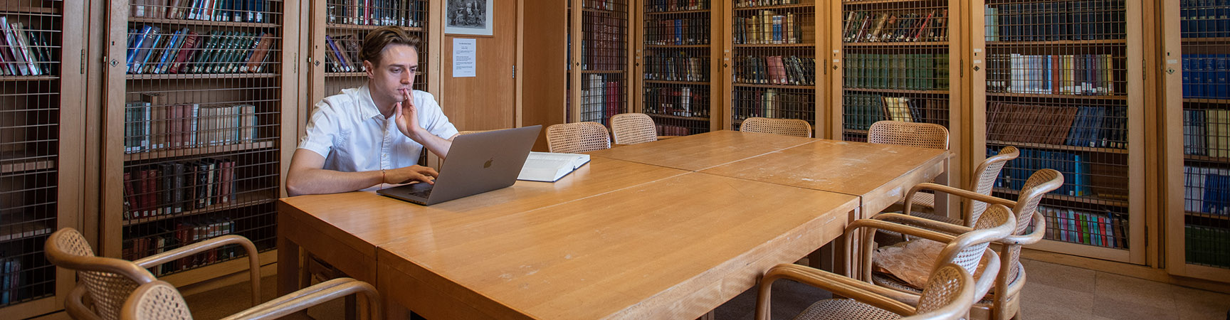 A student sits a table with six chairs around it