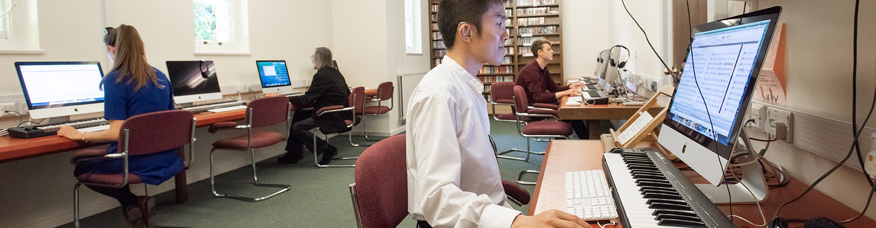 A student sitting in front of a keyboard hooked up to a computer