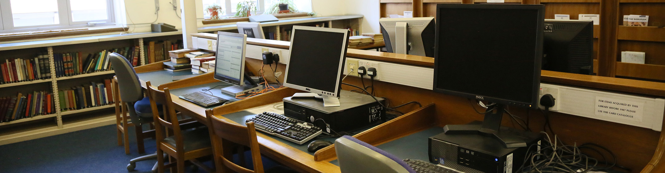 A row of three desktop computers on a wooden desk