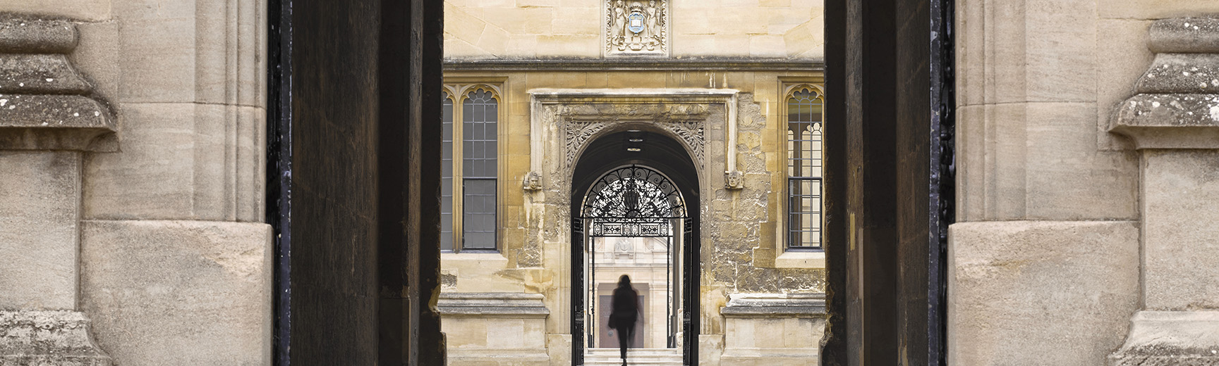 The silhouette of a person walking through an archway into the Old Bodleian Library