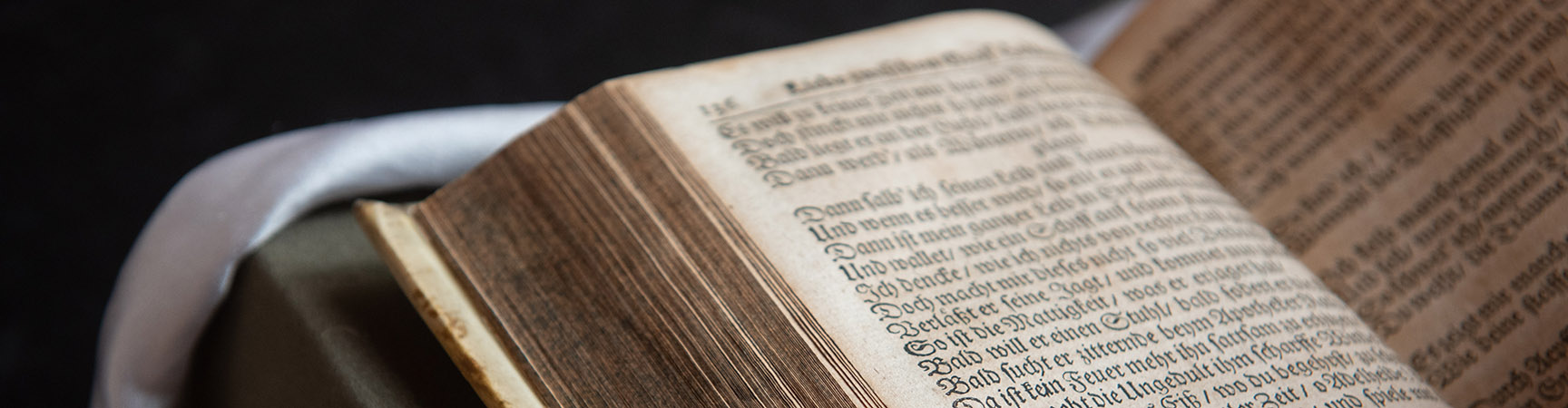 A detail of a rare book - it is open half way though with dark calligraphy writing on the page