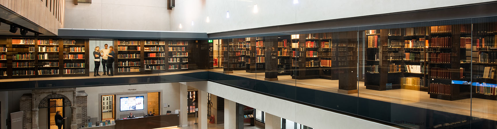 A two-storey height room with a glass mezzanine filled with bookshelves
